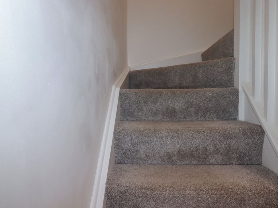 A staircase with gray carpet at Buttercup Cottage in St Merryn