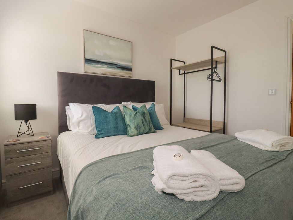 A bedroom with a bed and bedside table at Buttercup Cottage in St Merryn