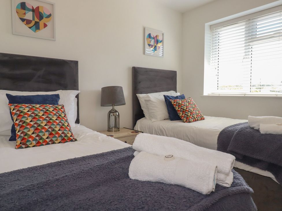 A bedroom with two beds and wall art at Buttercup Cottage St Merryn