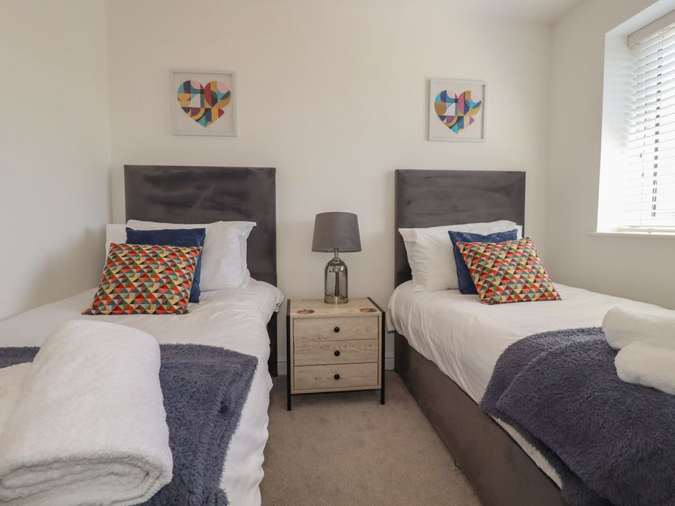 A bedroom with two beds and a bedside table at Buttercup Cottage St Merryn