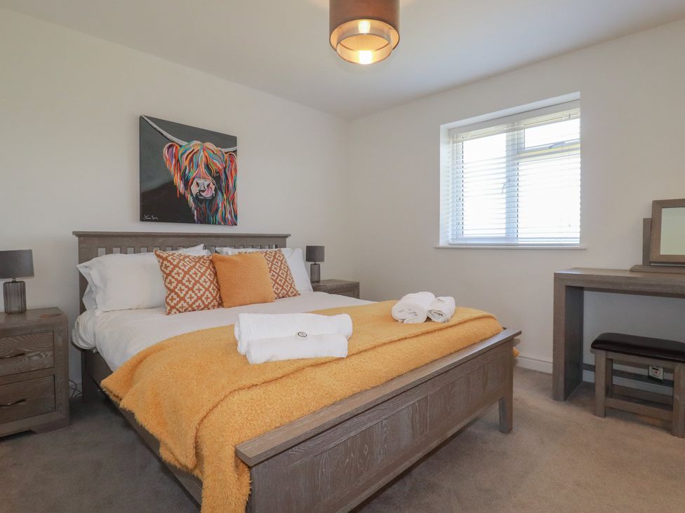 A bedroom with a bed and desk at Buttercup Cottage in St Merryn