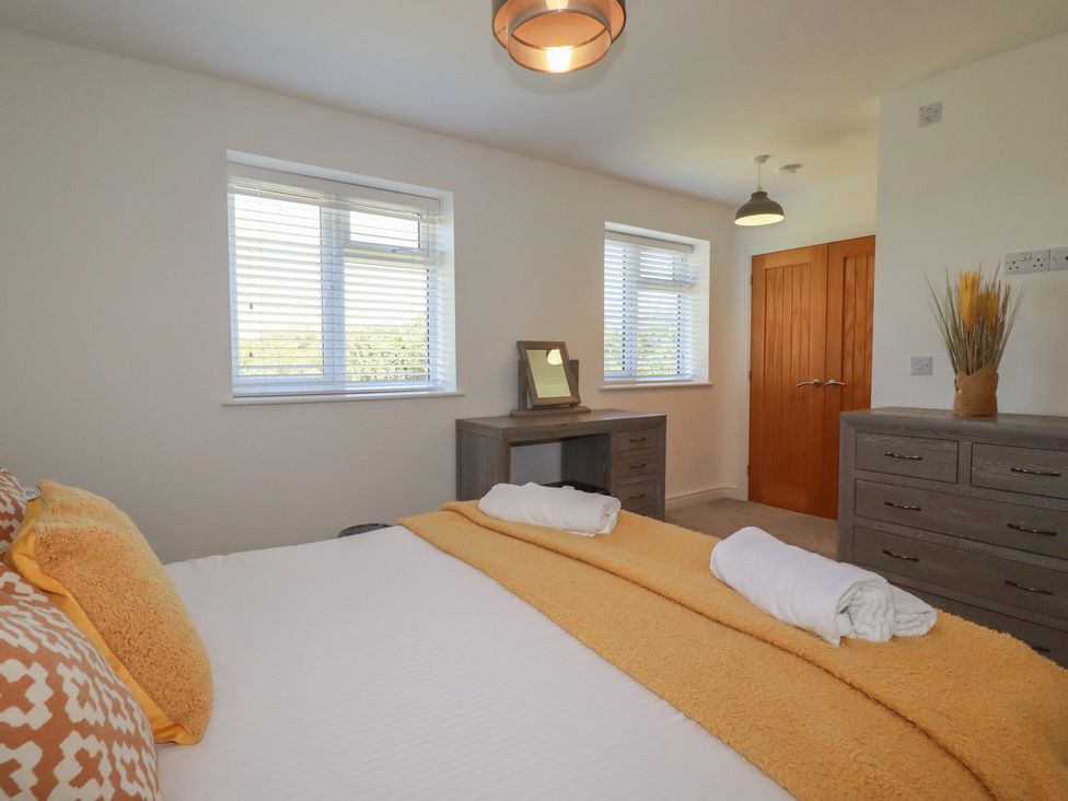 A bedroom with a bed and desk at Buttercup Cottage in St Merryn