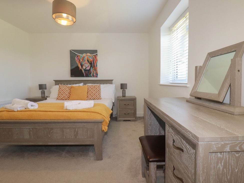 A bedroom with a bed and desk at Buttercup Cottage in St Merryn