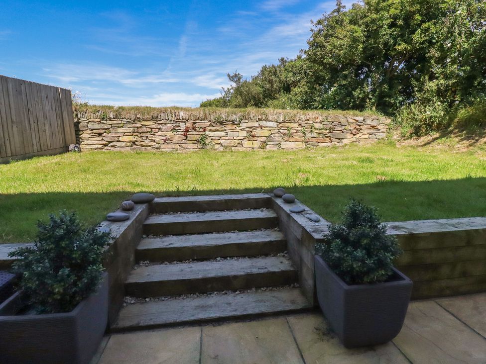 A garden with steps leading to a stone wall at Buttercup Cottage St Merryn