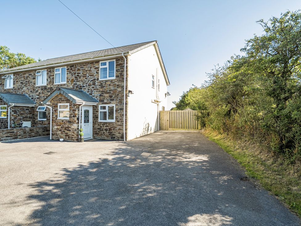 A house with a driveway and fence at Buttercup Cottage in St Merryn