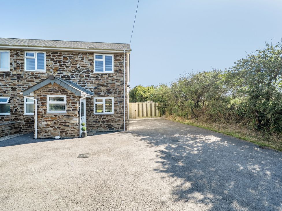 An outdoor view of a stone house with a driveway at Buttercup Cottage St Merryn