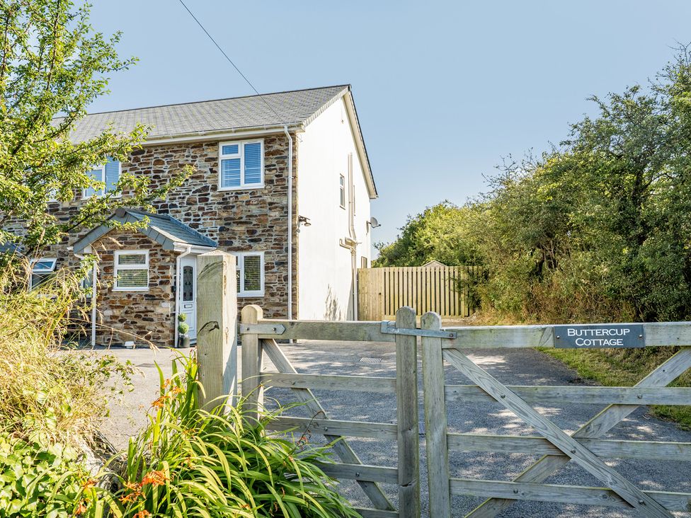 An outdoor area with a gate and a cottage at Buttercup Cottage in St Merryn