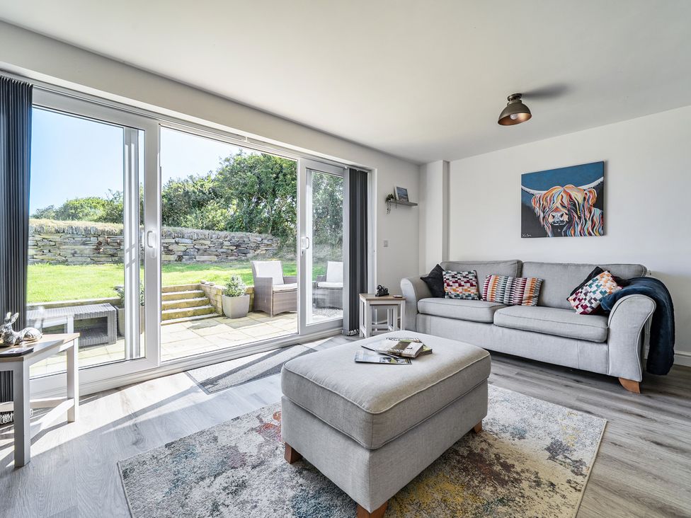 A living room with a sliding door to an outdoor area at Buttercup Cottage St Merryn