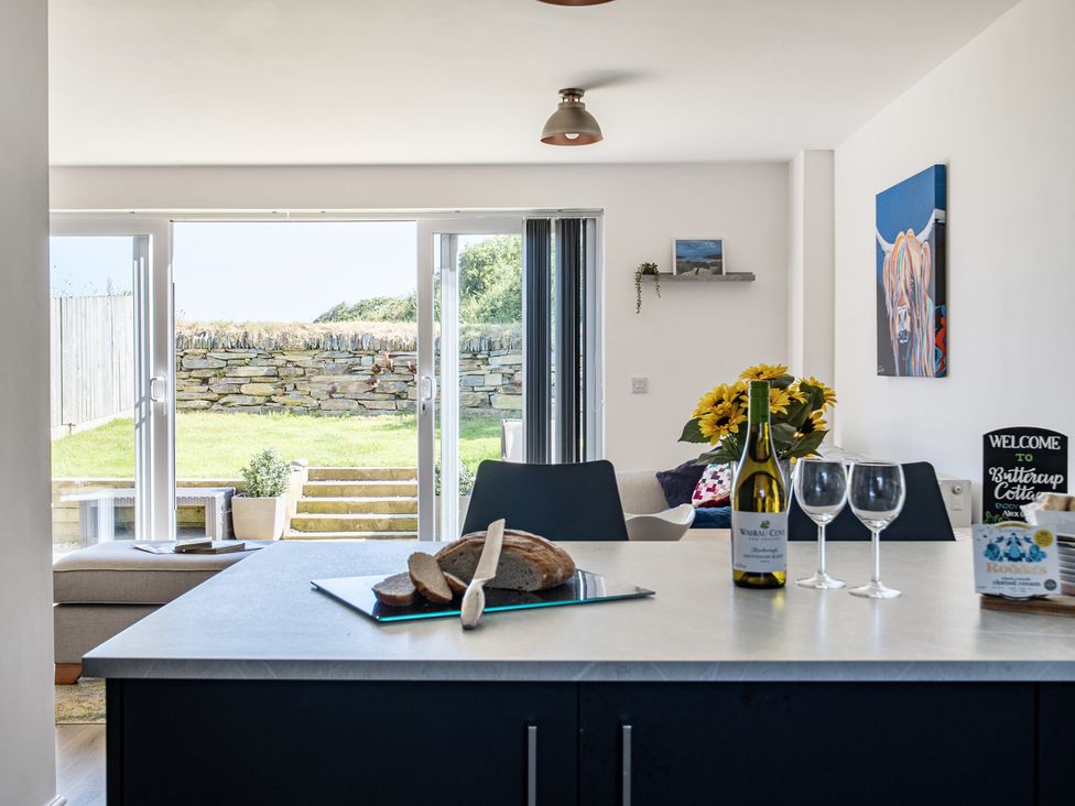 A kitchen with an island and seating area at Buttercup Cottage in St Merryn