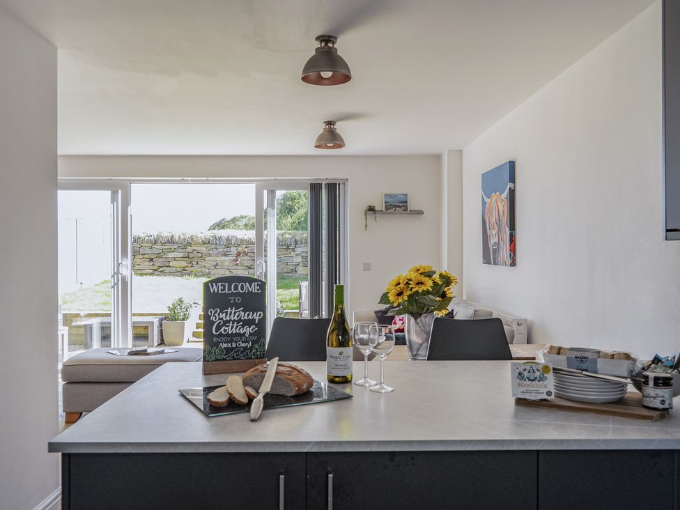 A kitchen with a welcome sign and dining area at Buttercup Cottage St Merryn