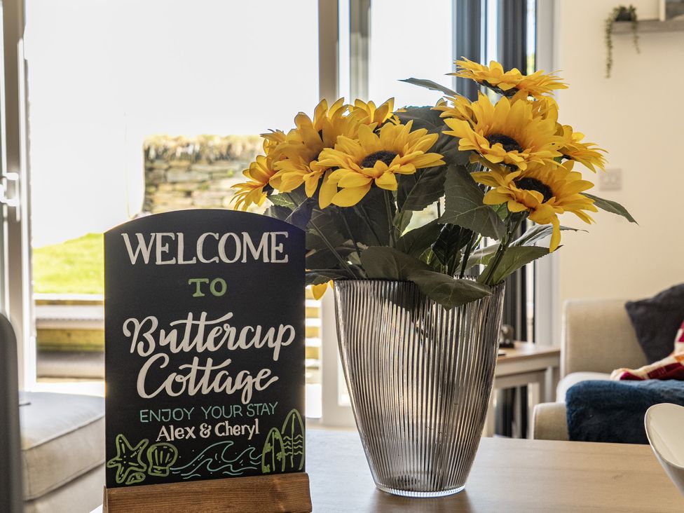 A welcome sign and sunflowers in a vase at Buttercup Cottage in St Merryn