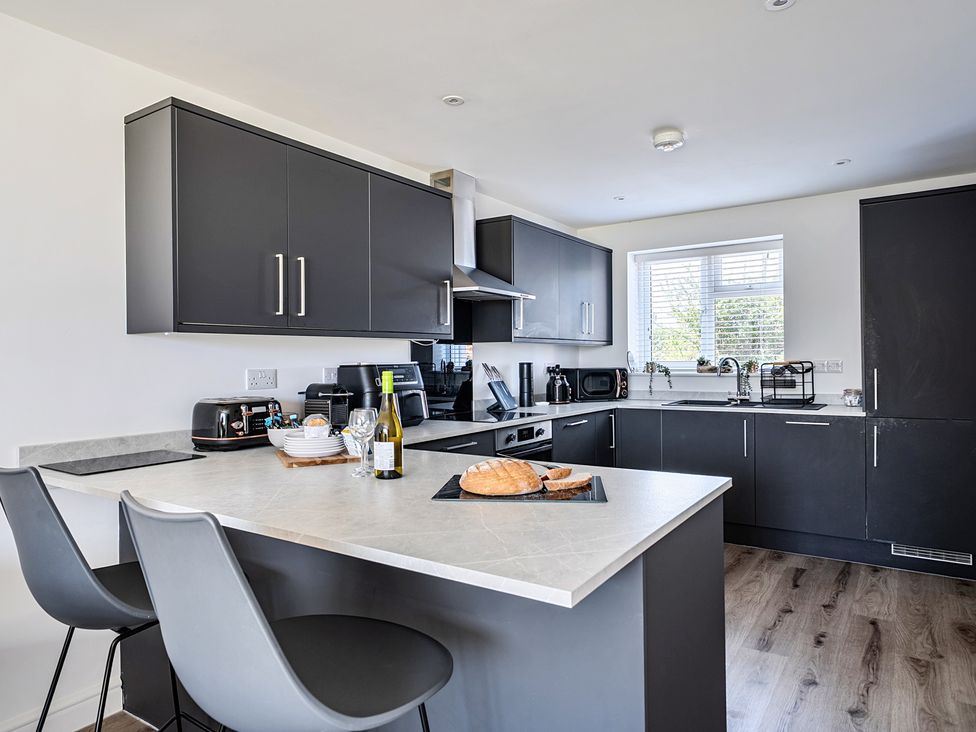 A kitchen with black cabinets and appliances at Buttercup Cottage in St Merryn