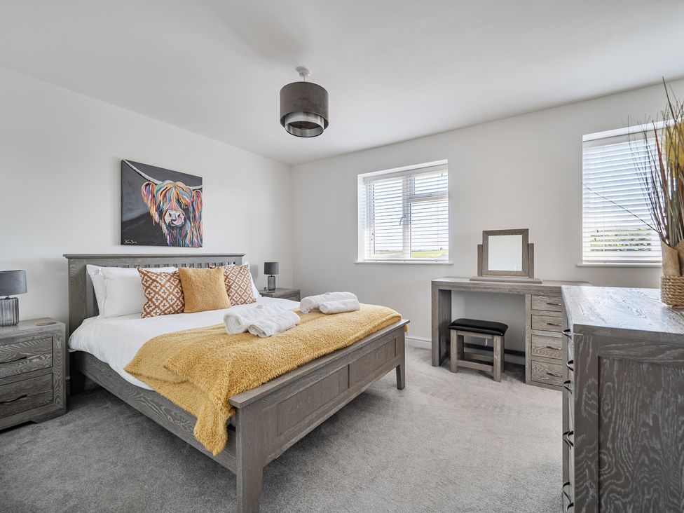 A bedroom with a bed and desk at Buttercup Cottage in St Merryn