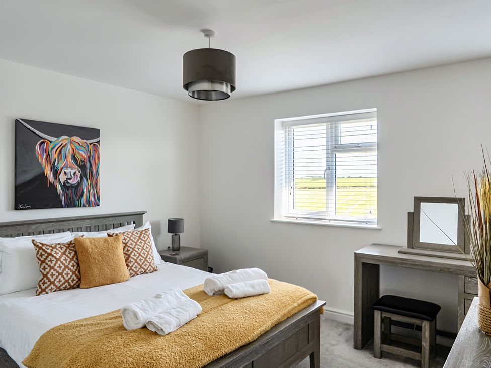 A bedroom with a bed and desk at Buttercup Cottage in St Merryn