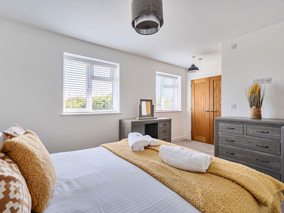 A bedroom with a bed and a dressing table at Buttercup Cottage in St Merryn