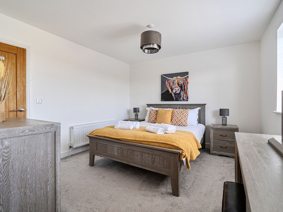 A bedroom with a bed and decorative art at Buttercup Cottage in St Merryn