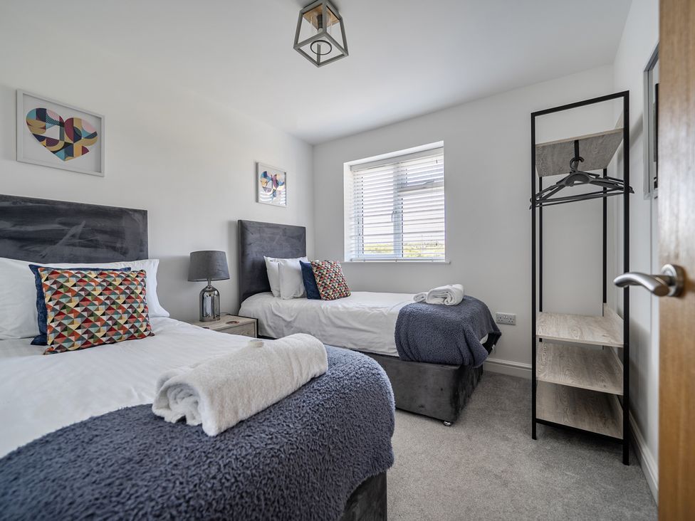A bedroom with two beds and a clothes rack at Buttercup Cottage St Merryn