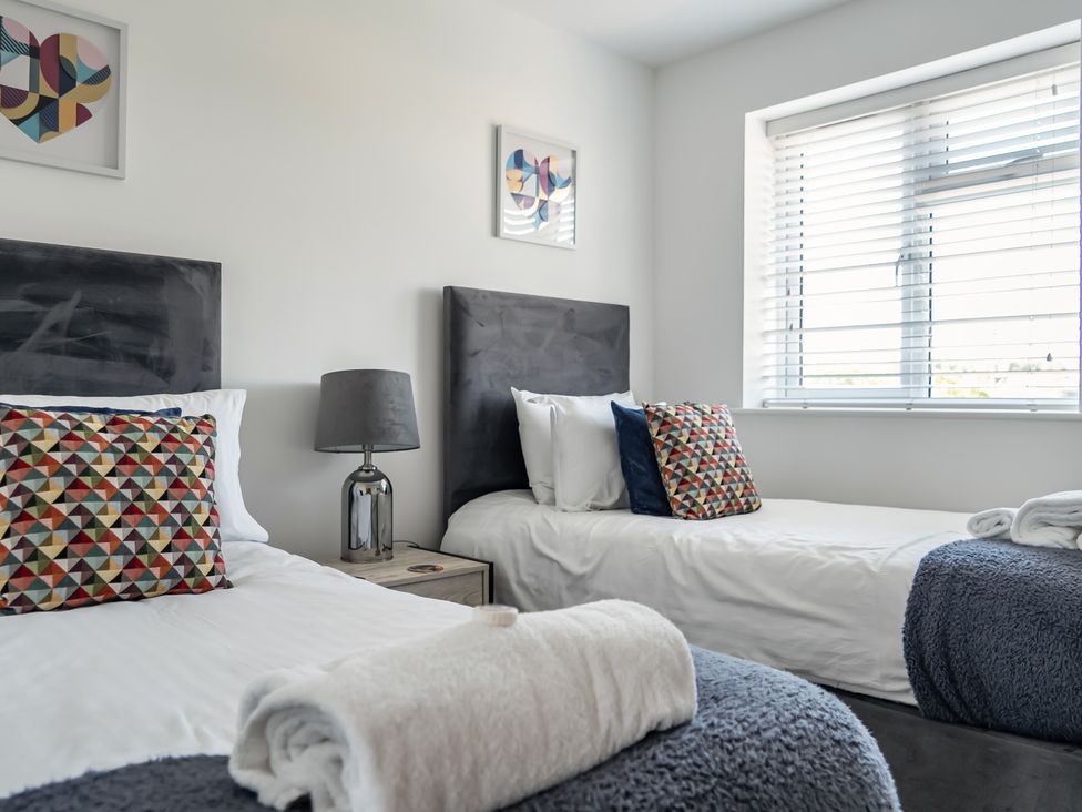 A bedroom with two beds and a window at Buttercup Cottage in St Merryn