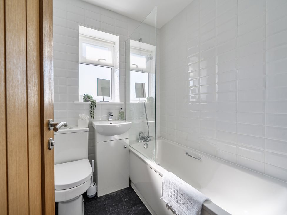 A bathroom with a toilet, sink and bathtub at Buttercup Cottage St Merryn