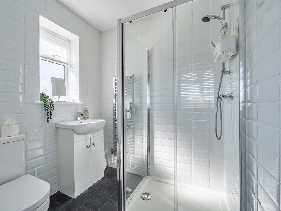 A bathroom with a sink, shower, and toilet at Buttercup Cottage in St Merryn
