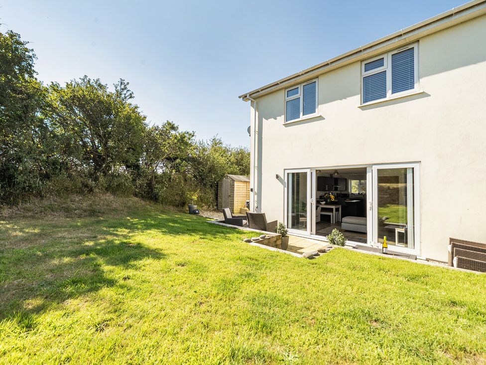 A garden with a house and outdoor furniture at Buttercup Cottage in St Merryn