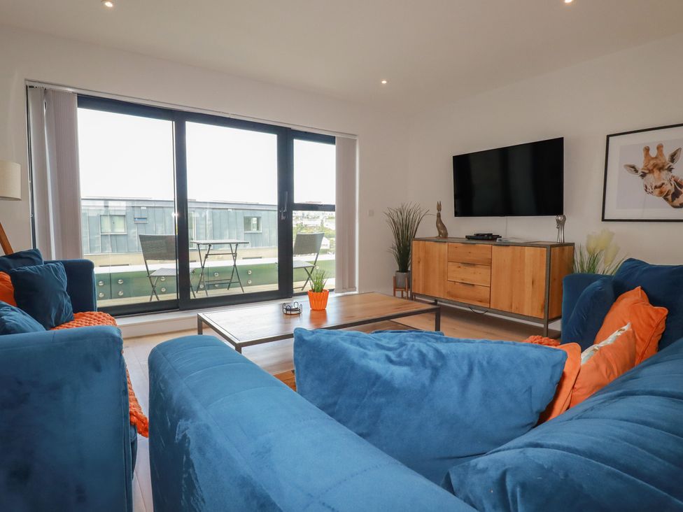 A living room with a television and a balcony at Seascape in Newquay