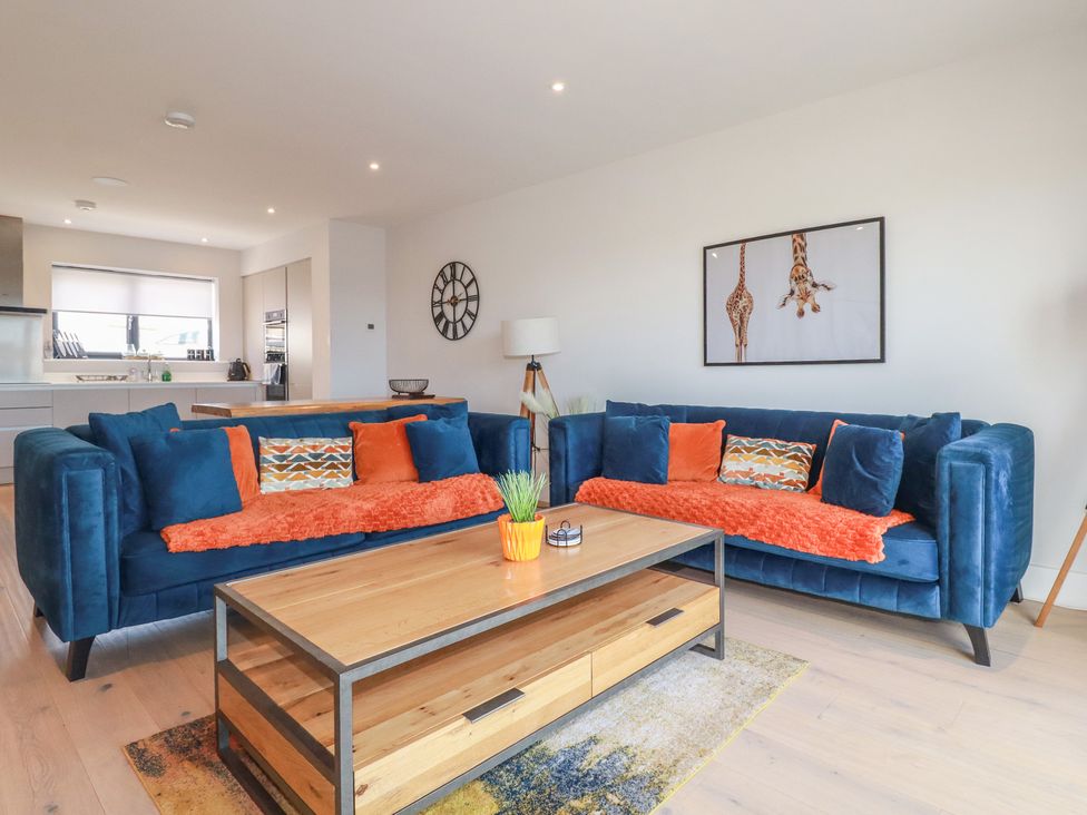 A living room with blue sofas and a wooden coffee table at Seascape in Newquay