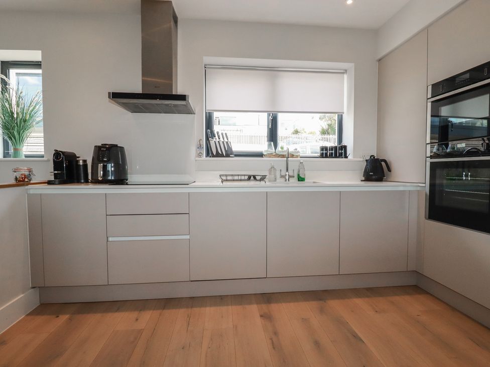 A kitchen with cabinets, sink, and appliances at Seascape in Newquay