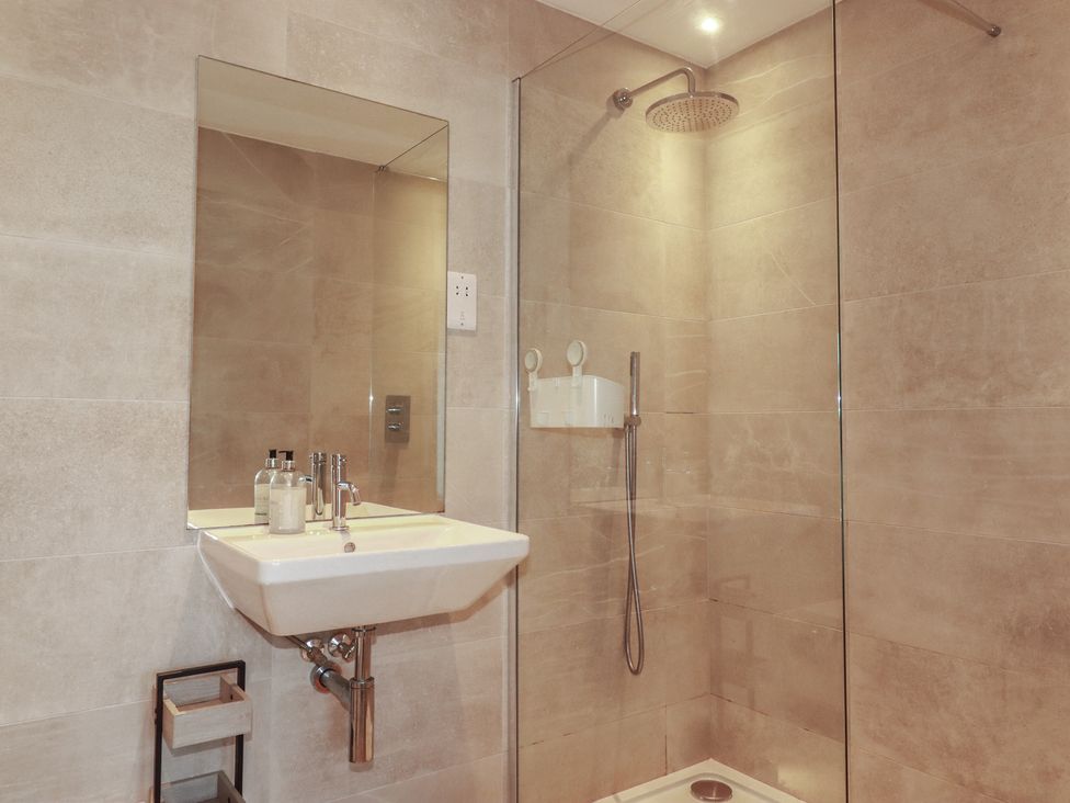 A bathroom with a sink, mirror, and shower at Seascape in Newquay