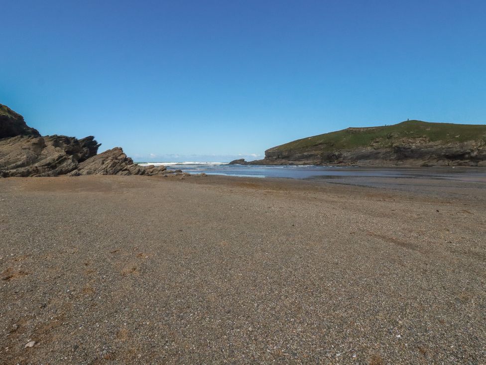 A beach with sand, rocks, and ocean waves at Seascape in Newquay