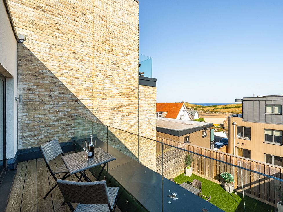 A balcony with a table and chairs overlooking the landscape at Seascape in Newquay