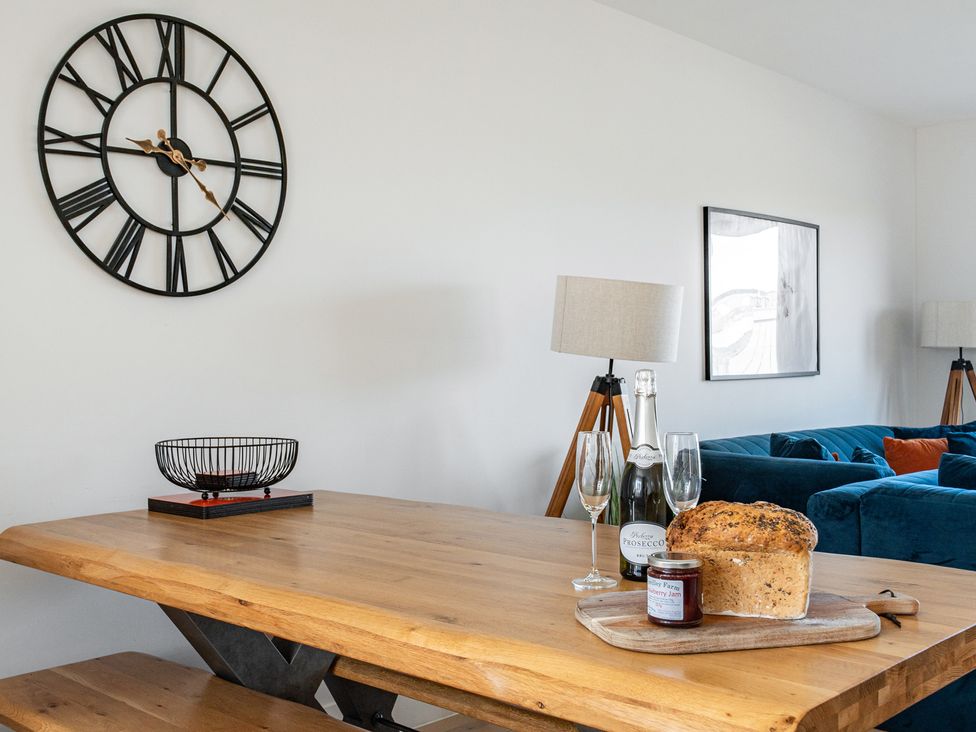 A dining room with a table, clock, glasses, and bread at Seascape in Newquay