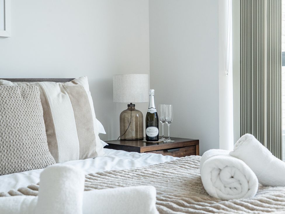 A bedroom with a bed and a bottle of Prosecco on a table at Seascape in Newquay