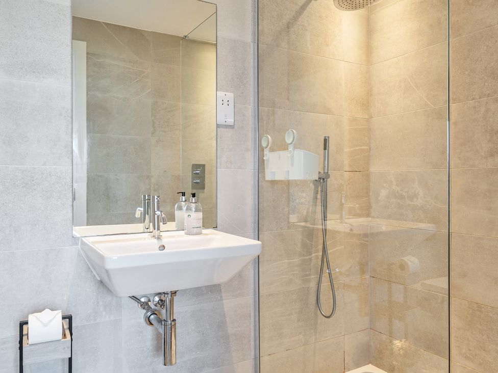 A bathroom with a sink shower and mirror at Seascape in Newquay