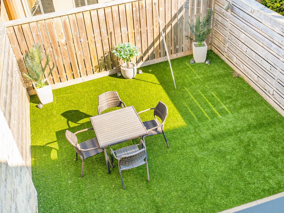 A garden with a table and chairs on artificial grass at Seascape in Newquay