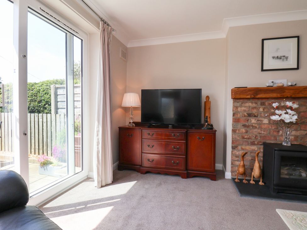 A living room with a television and cabinets at Wheeldale Cottage in Goathland