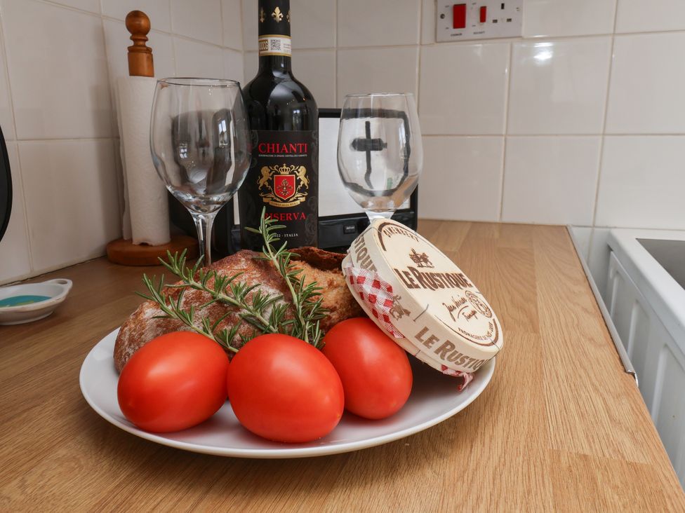 A kitchen with a wine bottle wine glasses bread tomatoes and cheese at Wheeldale Cottage Goathland