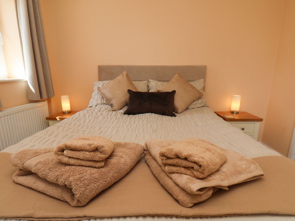A bedroom featuring a bed with linens and towels at Wheeldale Cottage in Goathland