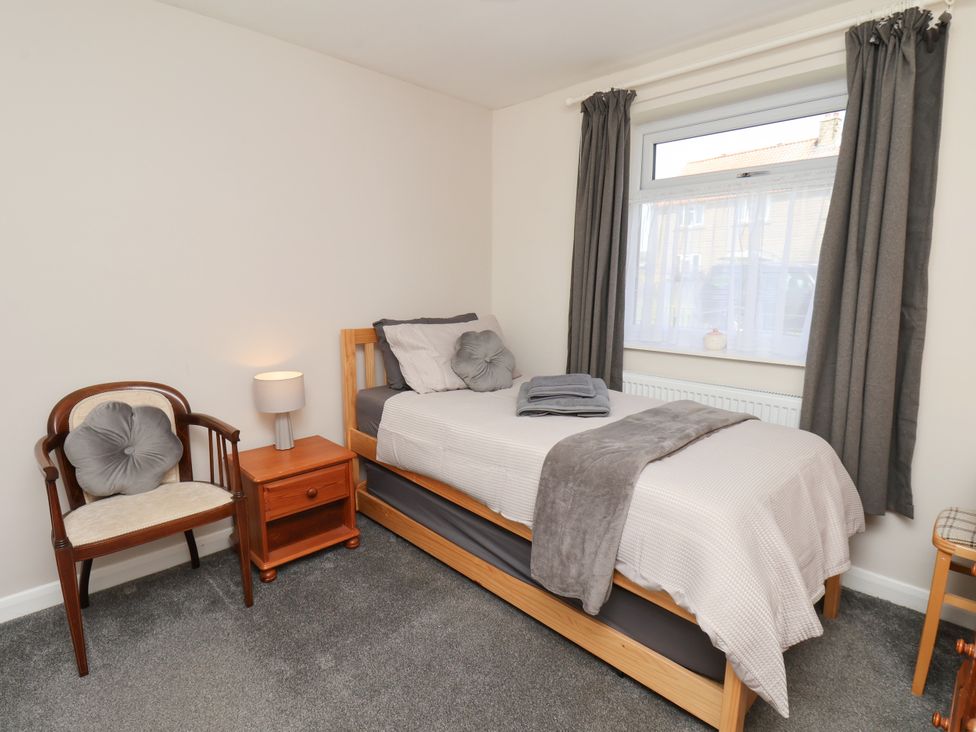 A bedroom with a bed and a chair at Wheeldale Cottage in Goathland