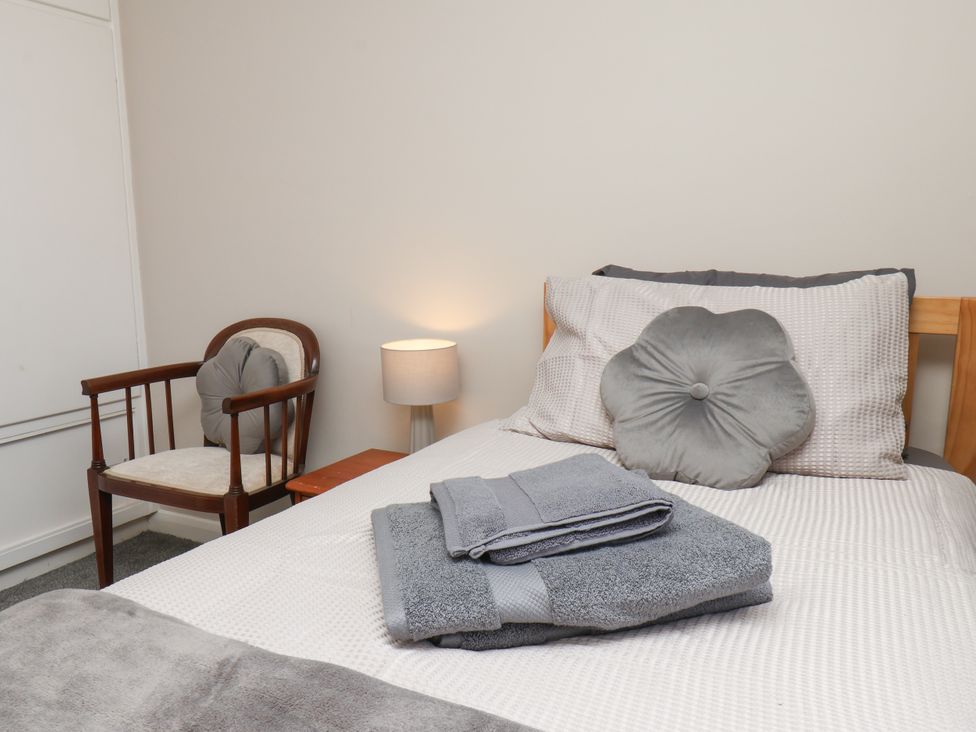 A bedroom with a bed, towels, lamp, and chair at Wheeldale Cottage in Goathland