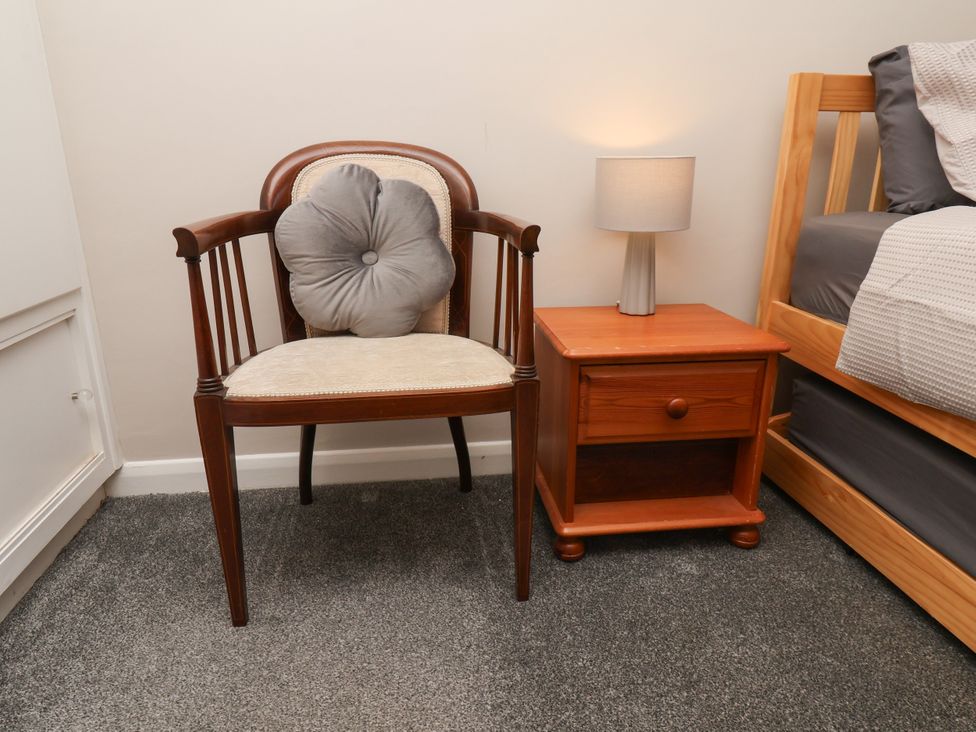 A bedroom with a chair, bedside table, and lamp at Wheeldale Cottage in Goathland