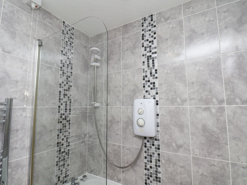 A bathroom with a shower and tiled walls at Wheeldale Cottage in Goathland