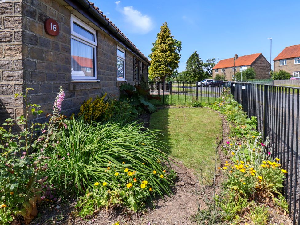 A garden with flowers and a fence at Wheeldale Cottage in Goathland