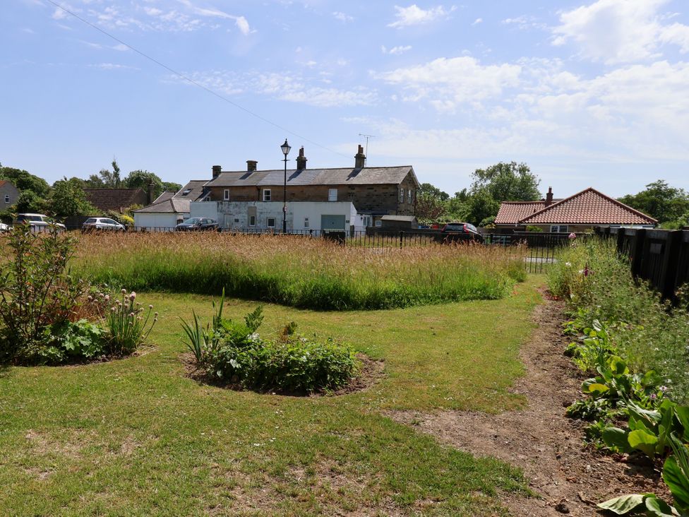 A garden with grass and flowerbeds at Wheeldale Cottage in Goathland