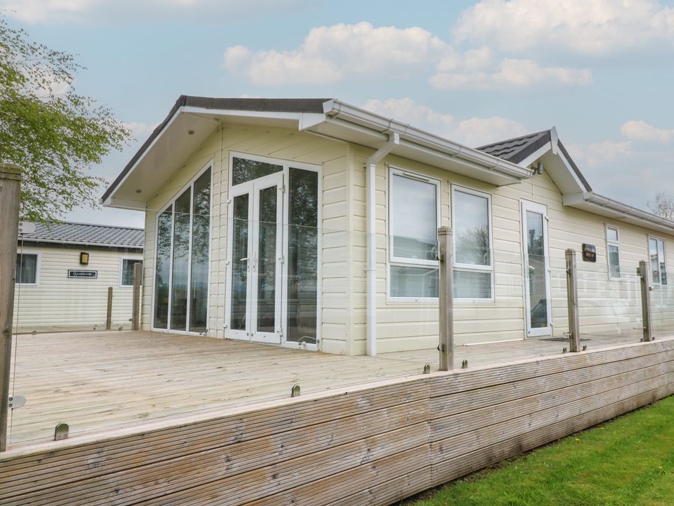 A house with a deck and multiple windows at Plot 34 Carlisle