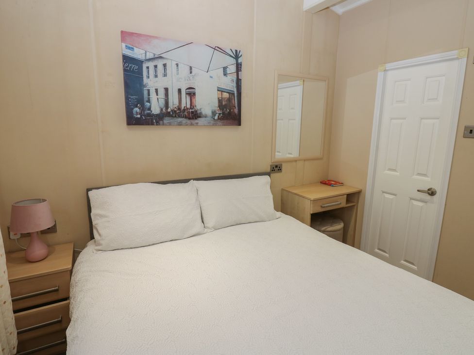 A bedroom with a bed, lamp, nightstand, and door at Plot 34 in Carlisle