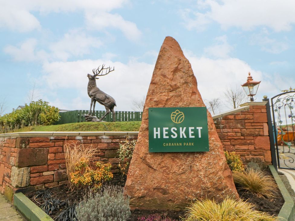 A sign for Hesket Caravan Park with a deer statue at the entrance of the park in Carlisle