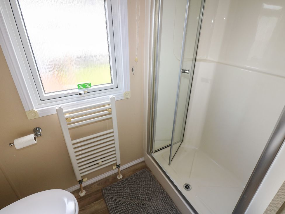 A bathroom with a shower, toilet, and towel rail at Plot 34 near Armathwaite