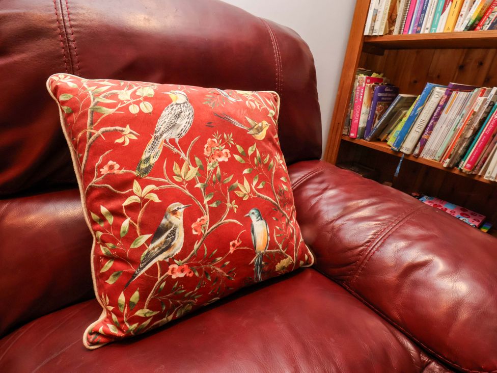 A cushion on a red couch with a bookshelf in the background at 7 Crestbrooke Northallerton