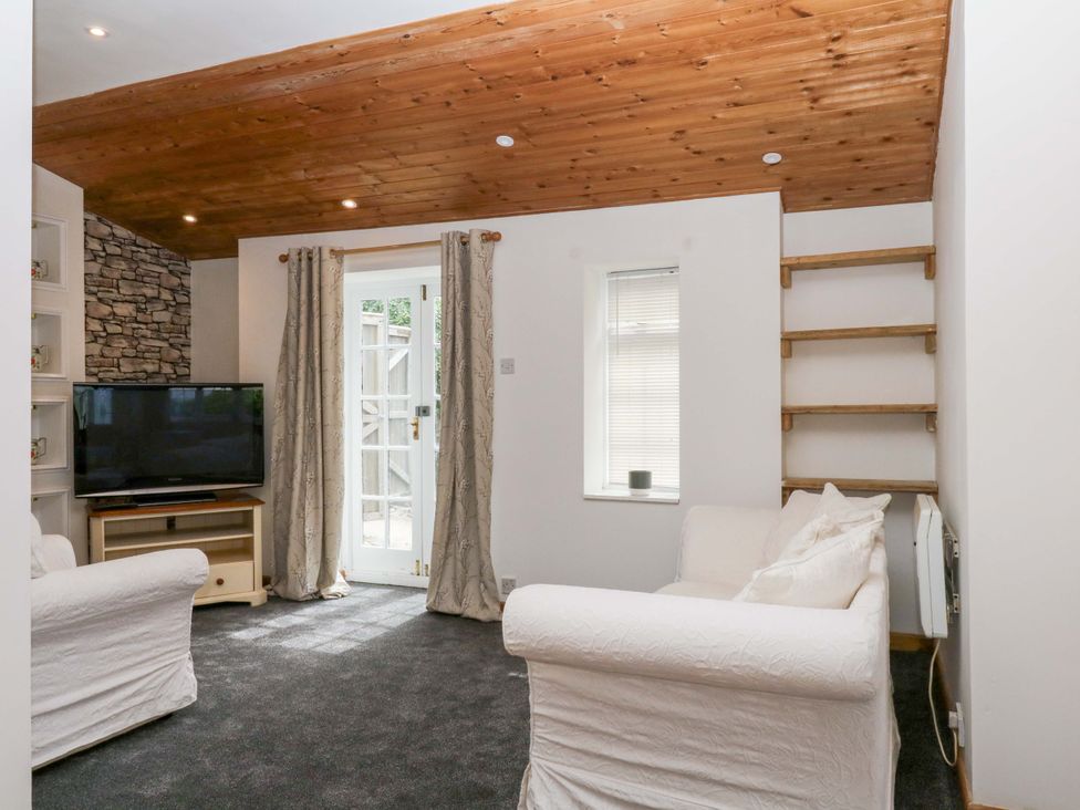 A living room with a television and door at The Headmasters Quarters in Chudleigh